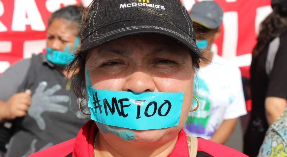 Female McDonalds worker at a protest with a #MeToo tape across her mouth